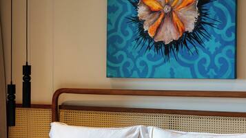 Quarto de hotel com cama, cabeceira e um quadro pendurado na parede.
