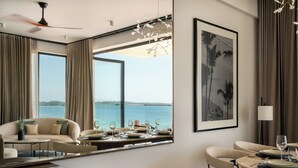 A modern hotel room with a large window, a dining area, and a ceiling fan. - Southbeach Weligama (Weligama)
