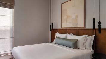Una habitación de hotel con una cama grande, cabecera de madera, un cuadro en la pared y una ventana con persianas.