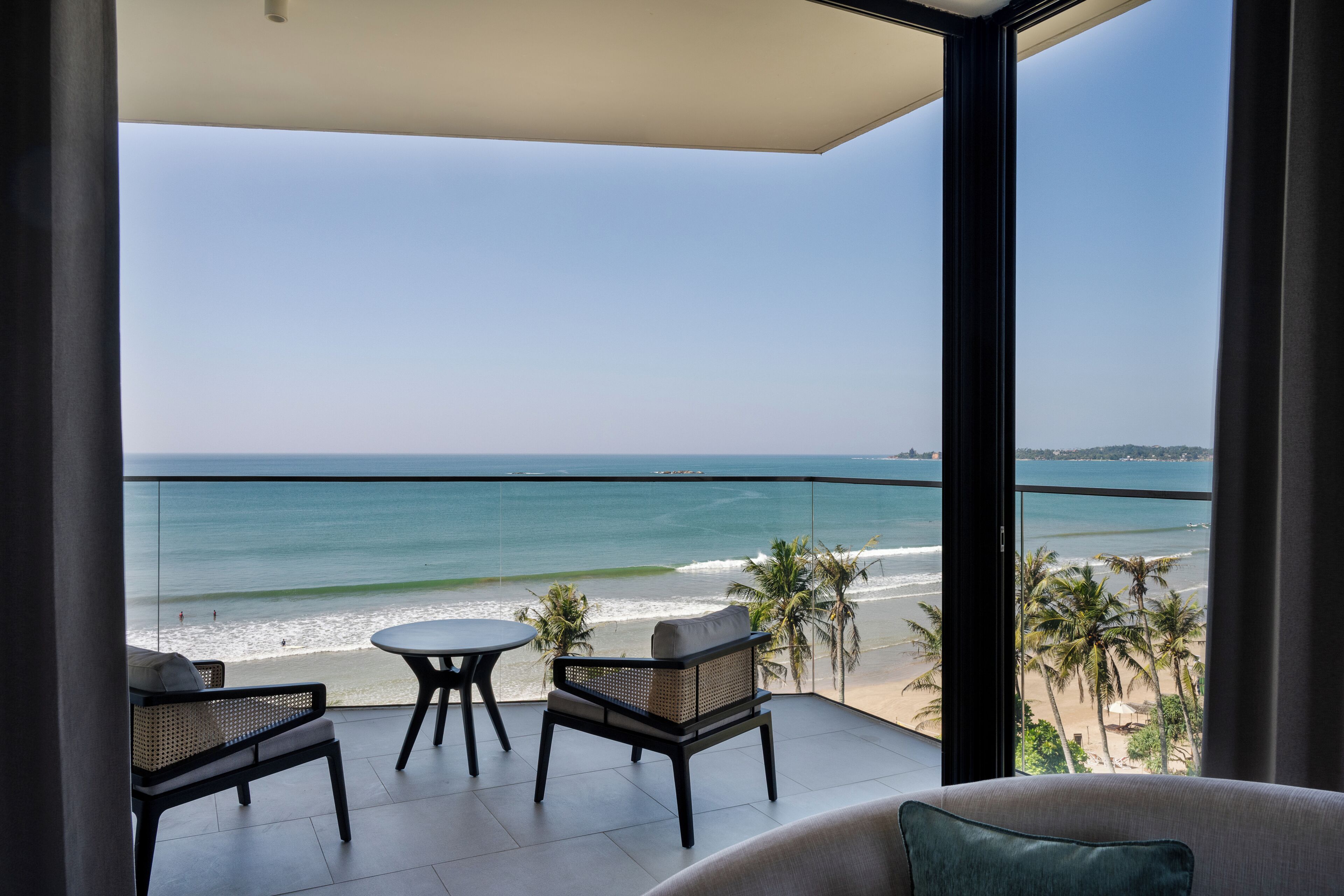 A balcony with a view of the beach and ocean.