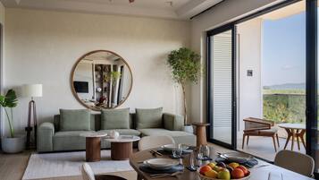 A modern living room with a dining area, a large mirror, and a view of the outdoors.