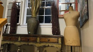 Une pièce dotée d’une grande fenêtre en arc de cercle, d’une horloge, d’un mannequin et d’une commode avec des paniers.
