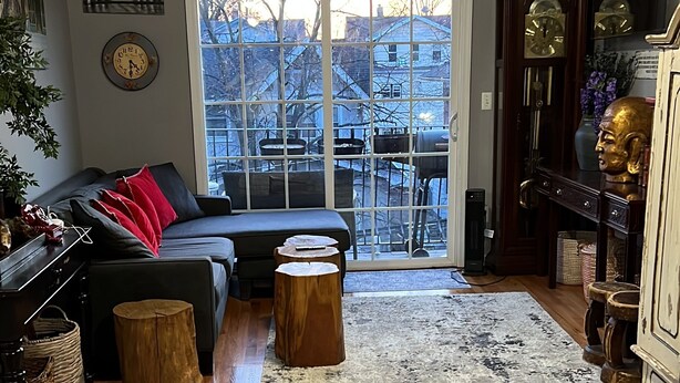 Un salon avec un canapé, un plancher en bois, une grande fenêtre et une vue sur l’extérieur.