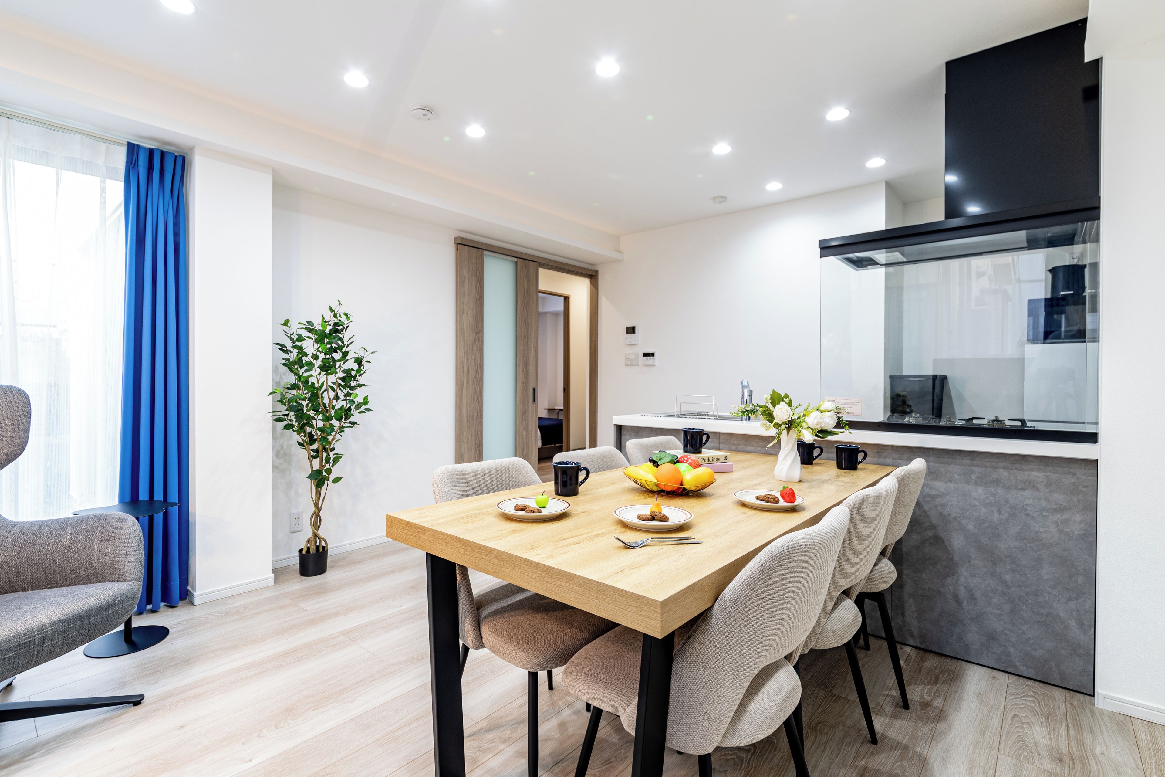 A modern dining area with a wooden table, chairs, and a potted plant.