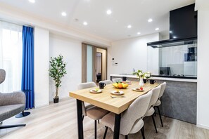 Espaço de refeições moderno com mesa de madeira, cadeiras e um vaso com planta.
