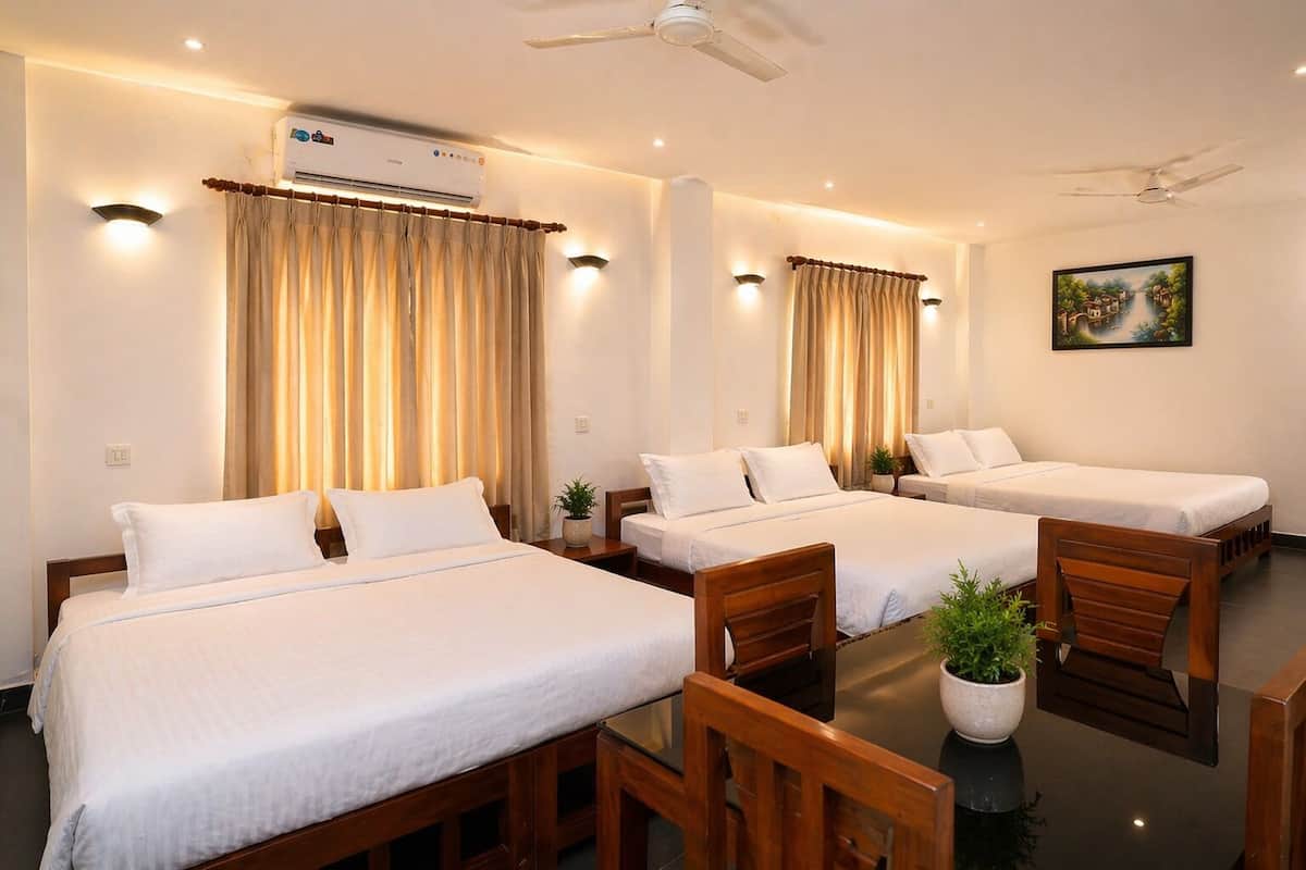 A hotel room with three single beds, a ceiling fan, an air conditioning unit, and a painting on the wall.