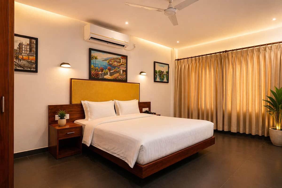 A hotel room with a bed, nightstand, wall-mounted air conditioner, ceiling fan, and a large window with curtains.