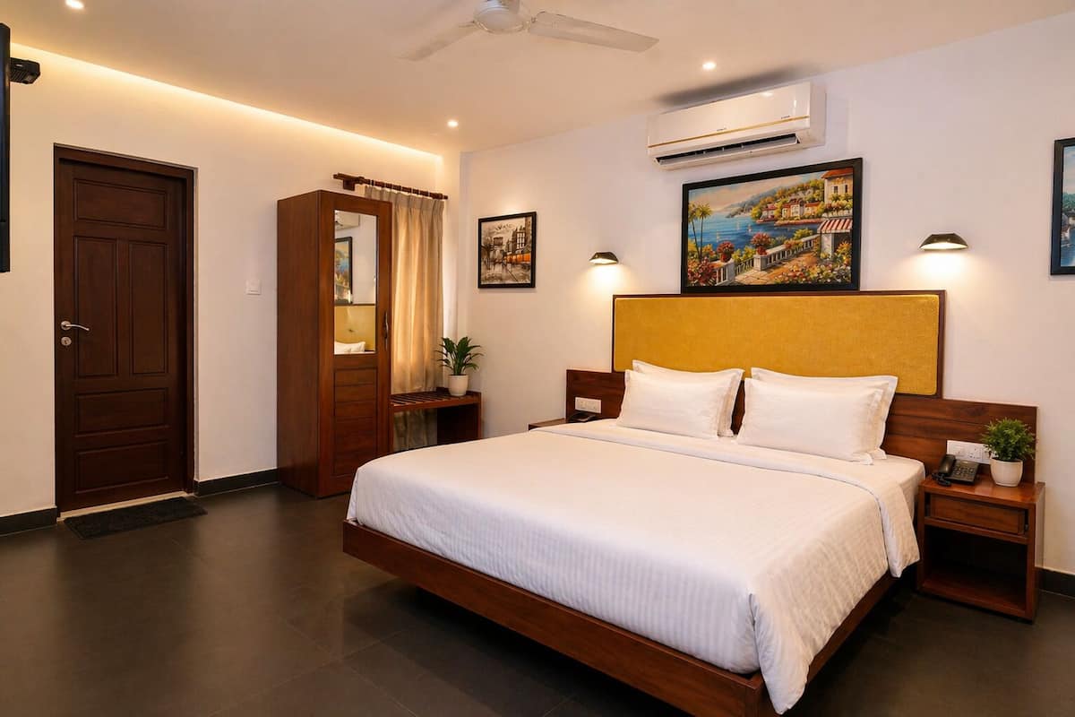 A bedroom with a bed, bedside tables, a wardrobe, an air conditioning unit, and artwork on the walls.