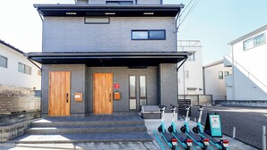 Un edificio moderno di due piani con una porta in legno, una panchina e scooter elettrici parcheggiati fuori.