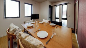 Un'area pranzo con un tavolo di legno apparecchiato per quattro persone, una televisione e un divano.