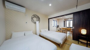 Camera d'albergo con due letti, una parete a motivi a scacchi, un moderno condizionatore d'aria e vista sulla sala da pranzo.