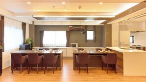 Una cocina moderna con una isla central, electrodomésticos integrados y un comedor con sillas.