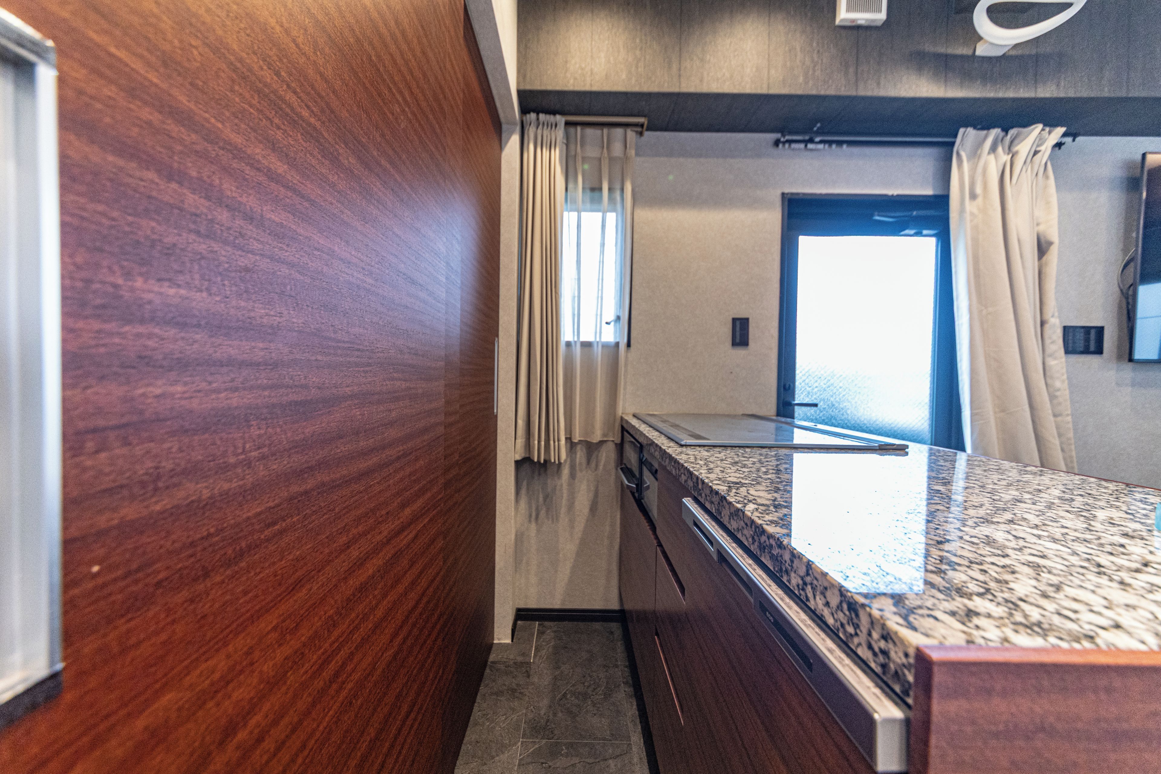 A bathroom with a wooden wall, a marble countertop, and a shower area.