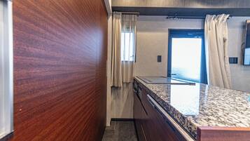 A bathroom with a wooden wall, a marble countertop, and a shower area.