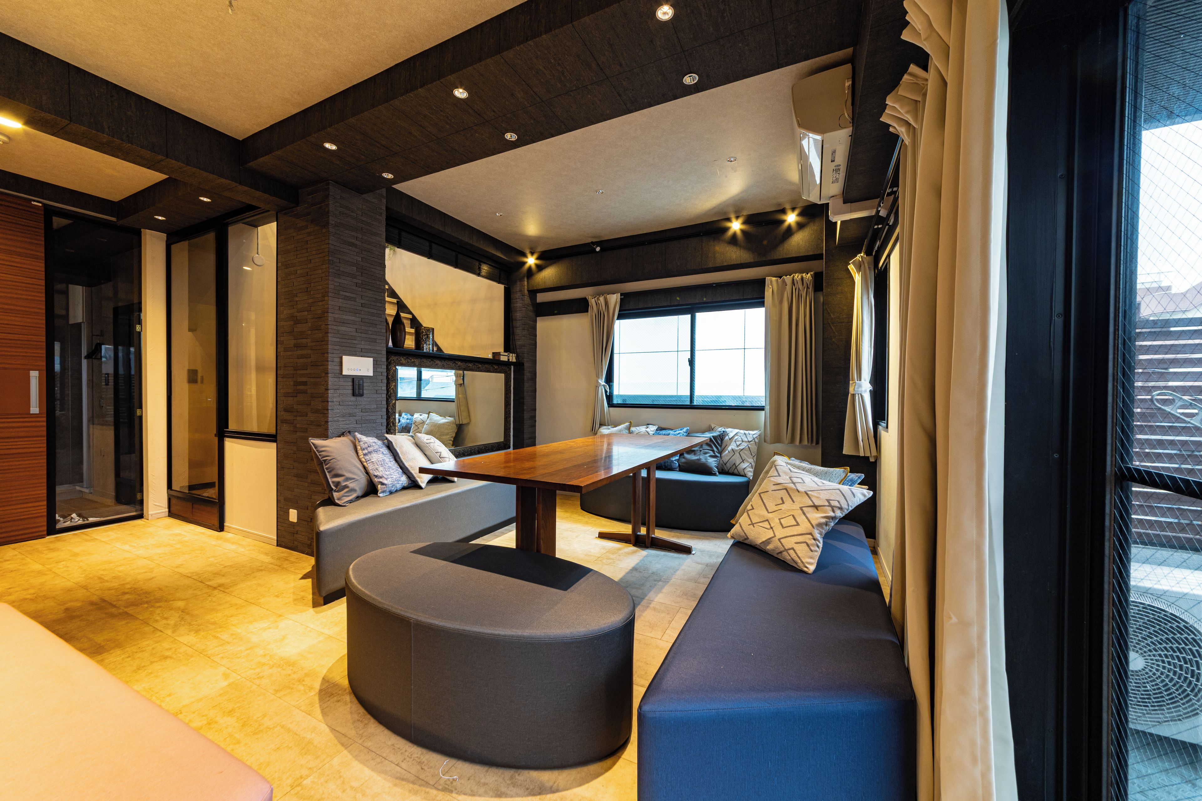 A modern interior with a sofa, ottoman, and a dining table.