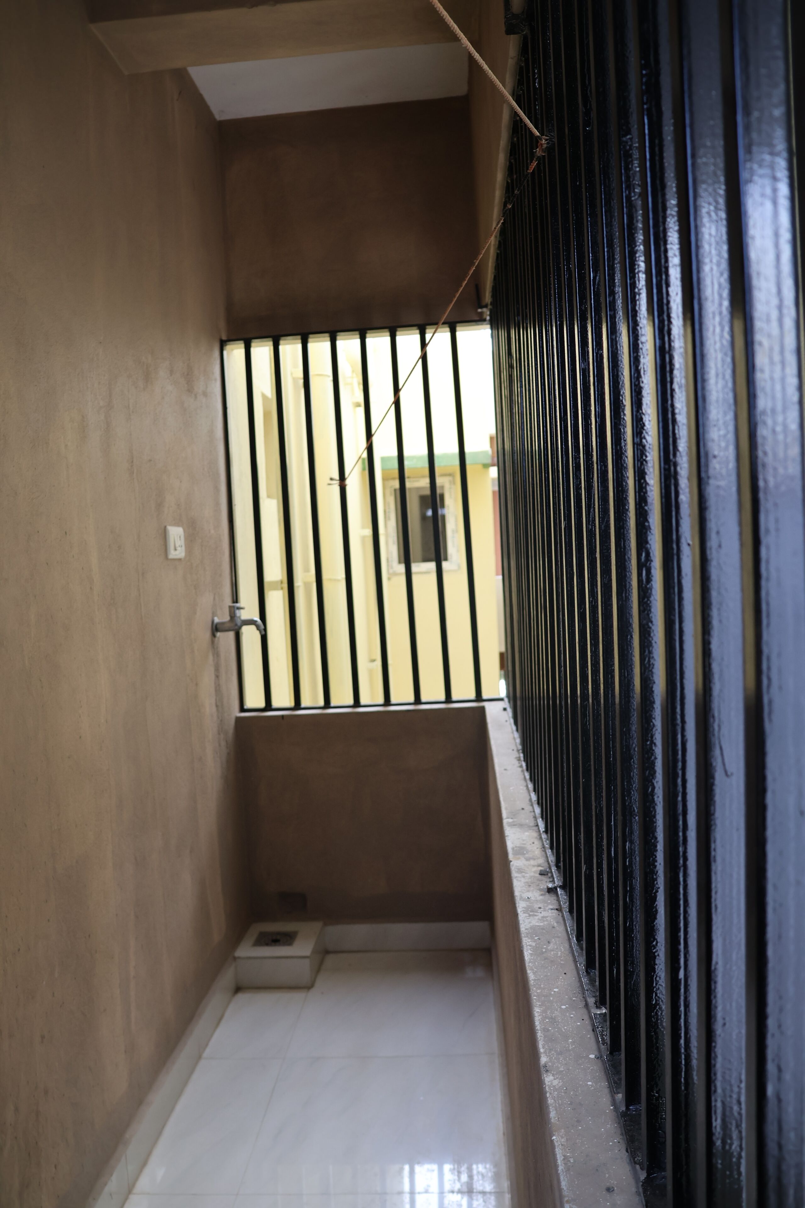 A narrow stairway with a black metal railing, a small window, and a visible door at the bottom.