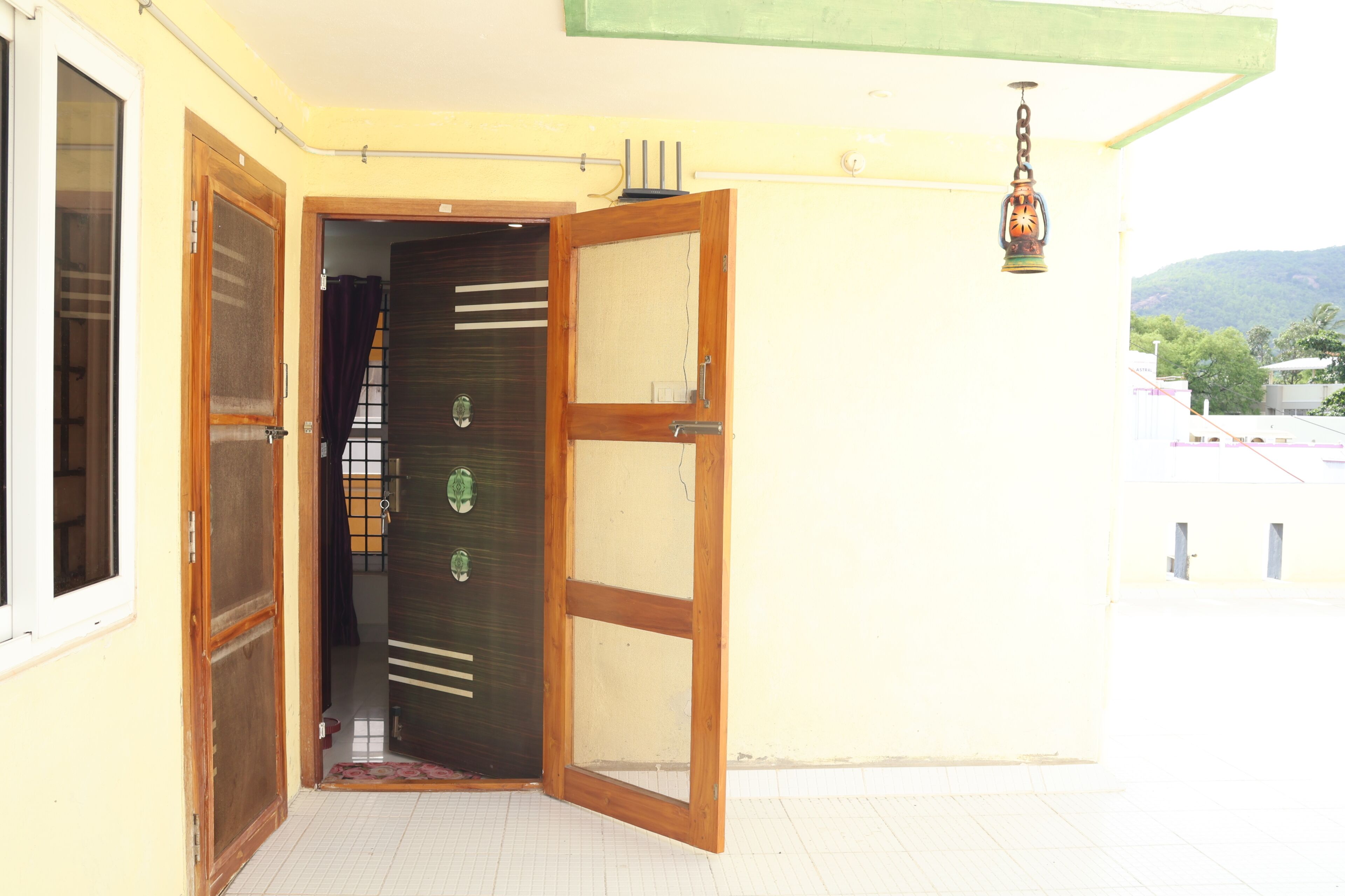 Una puerta con marco de madera y paneles de vidrio, que da paso a un espacio interior con piso de baldosas.