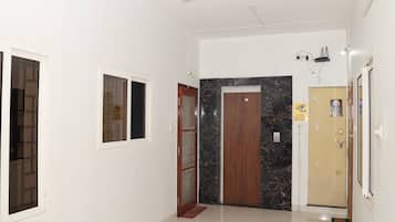 A hallway with a ceiling fan, a door with a marble surround, and a wall-mounted security camera.