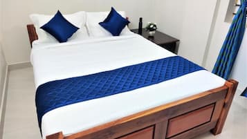 Una cama con estructura de madera, ropa de cama blanca y detalles en azul.