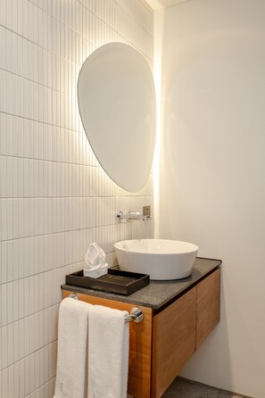 A bathroom with a white vessel sink, wooden vanity, and a large mirror. - Ecoverse Resort & Residence by OXO - Nyanyi Beach, Bali (Tabanan)