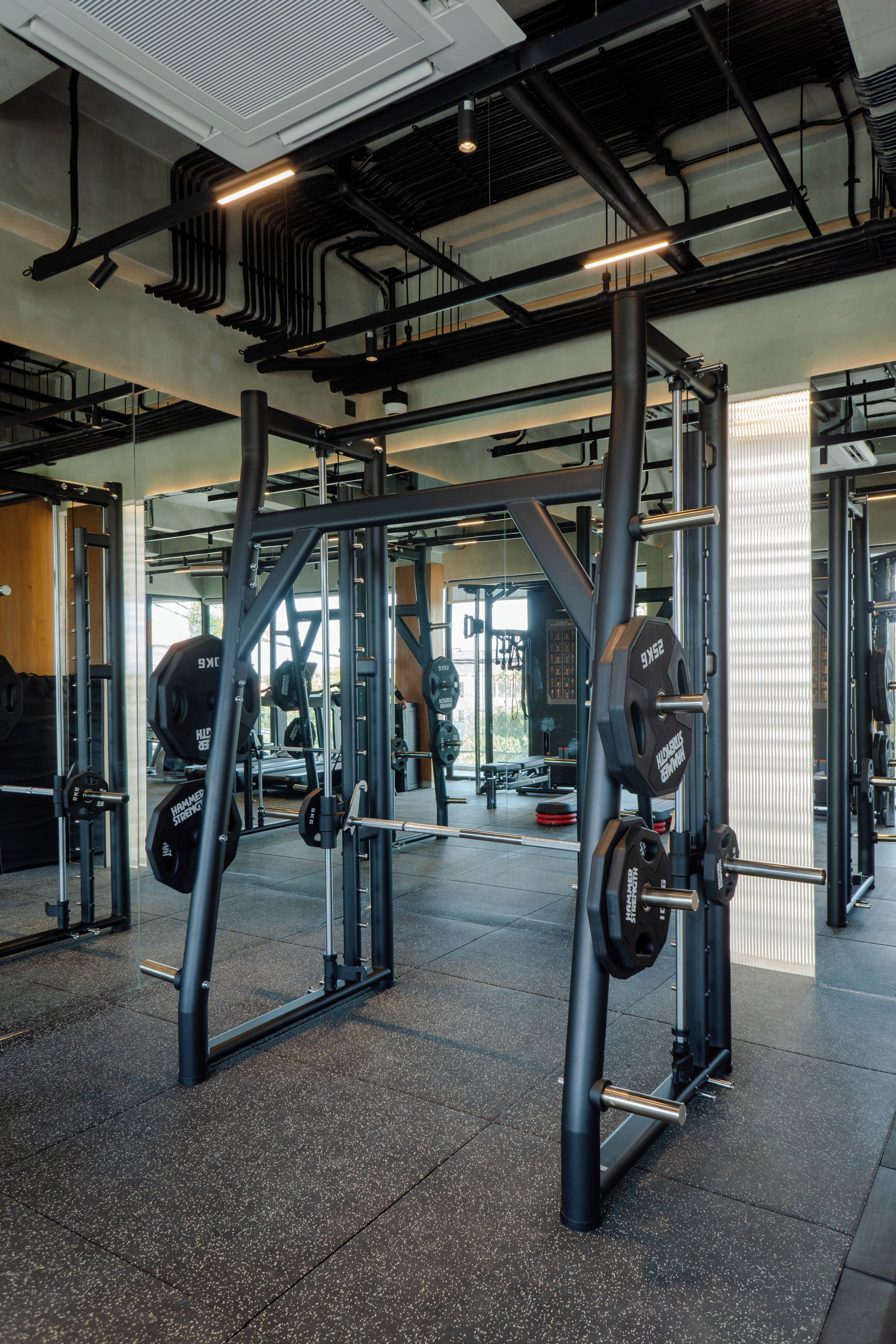 Ett gym med utrustning för styrketräning, inklusive en knäböjsställning och skivstänger.