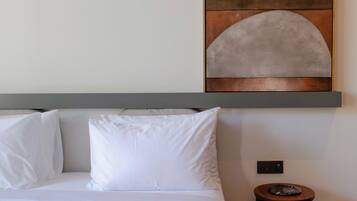 A neatly made bed with white linens, a headboard, and a small bedside table with a lamp.
