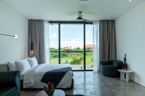 A modern hotel room with a bed, a green armchair, a small table, and a view of the outdoors. - Ecoverse Resort & Residence by OXO - Nyanyi Beach, Bali (Tabanan)