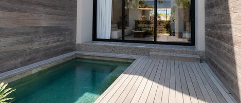 A modern house with a swimming pool, large windows, and a wooden deck.