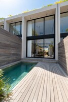 Ein modernes Haus mit Schwimmbad, großen Fenstern und einer Holzterrasse.