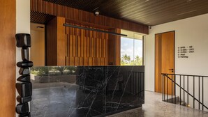 A modern interior with a black marble reception desk, wooden paneling, and a clear view of the outdoors.