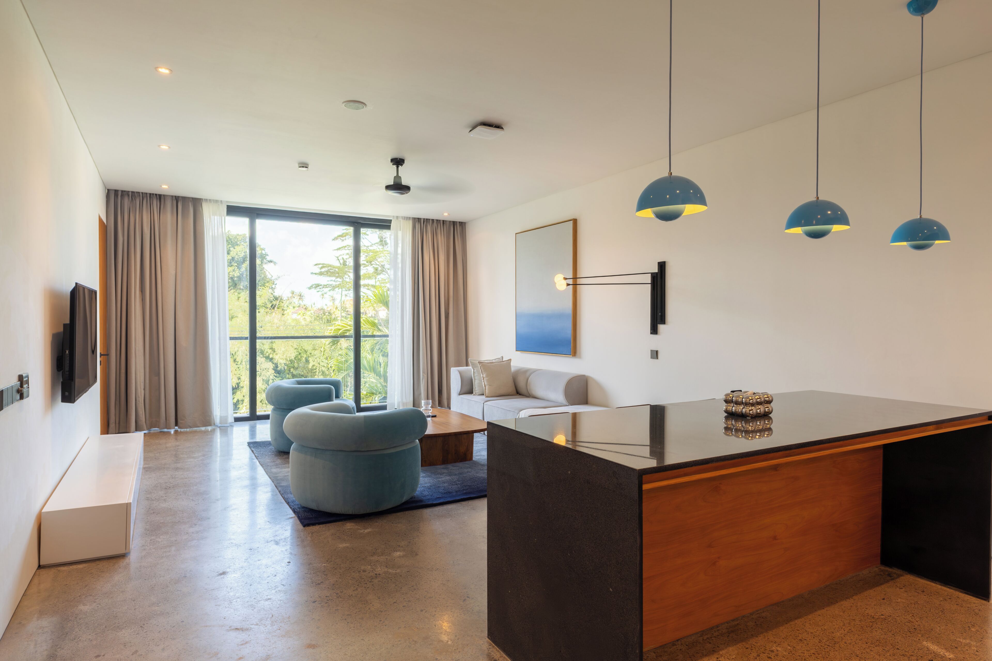 Una cocina moderna con una isla central, un área de comedor con sofá y un gran ventanal con cortinas.