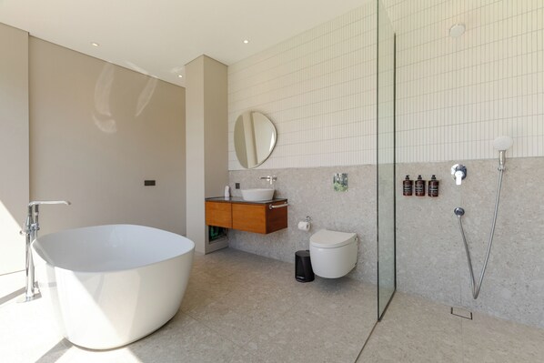A modern bathroom with a freestanding bathtub, a toilet, and a glass-enclosed shower area. - Ecoverse Resort & Residence by OXO - Nyanyi Beach, Bali (Tabanan)
