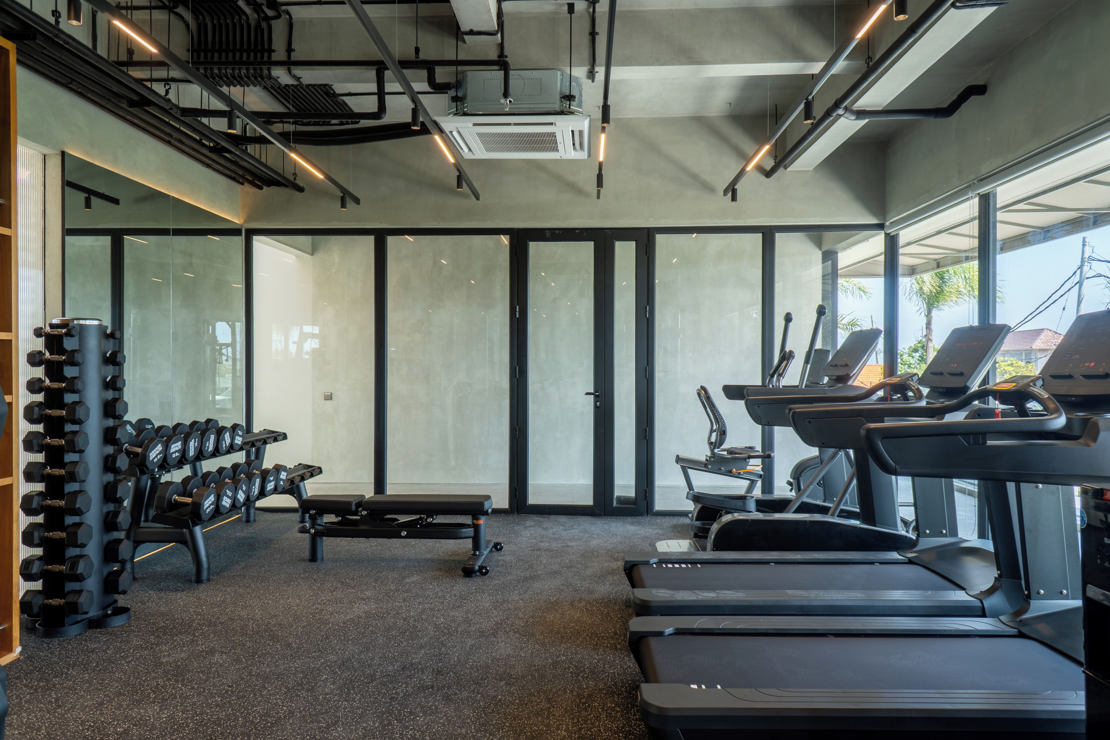 A gym with treadmills, dumbbells, and a bench.