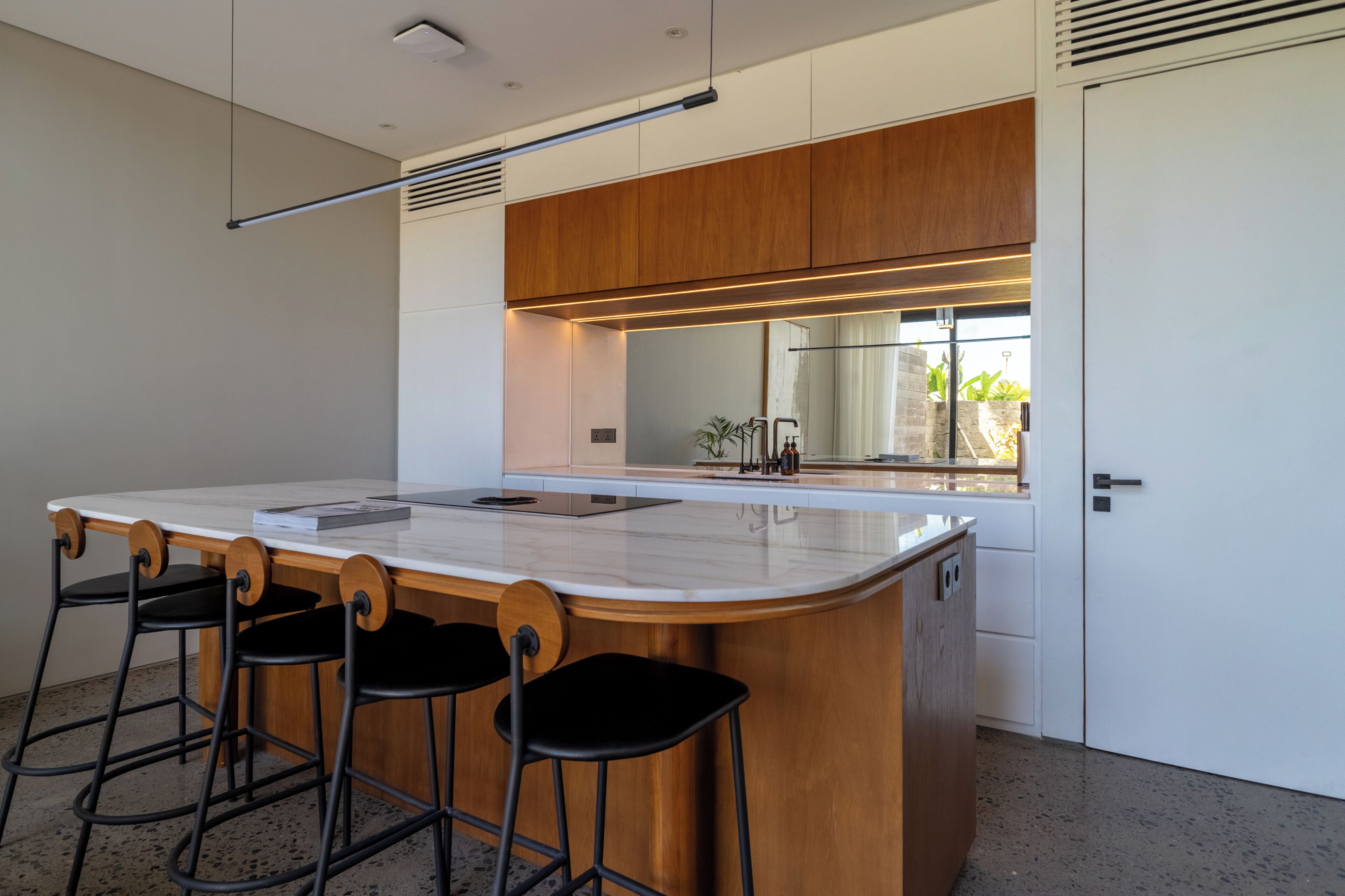 Una cucina moderna con una grande isola, sgabelli da bar e vista sull'esterno.