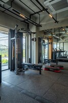 Ein Fitnessstudio mit verschiedenen Trainingsgeräten, darunter Kraftgeräte und Laufbänder.
