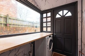 A laundry room with a washing machine, a window, and a door. - Largest Spacious 5 Bed Home w/ Garden & Games Parking near Hull Uni (Kingston upon Hull)