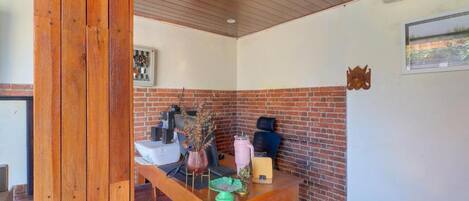 A room with a wooden table, a brick wall, and a ceiling fan.