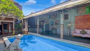 Un espace aménagé au bord de la piscine avec un chien, un canapé et une table.