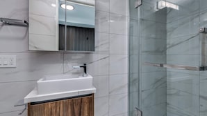 A modern bathroom with a marble sink, a mirror, and a glass-enclosed shower. - Luxury Apartment in Central Downtown Location (Vancouver)