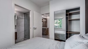 A modern bedroom with a large bed, a walk-in closet, and a shower area. - Luxury Apartment in Central Downtown Location (Vancouver)