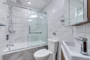 A modern bathroom with a glass-enclosed shower, a toilet, and a bathtub.