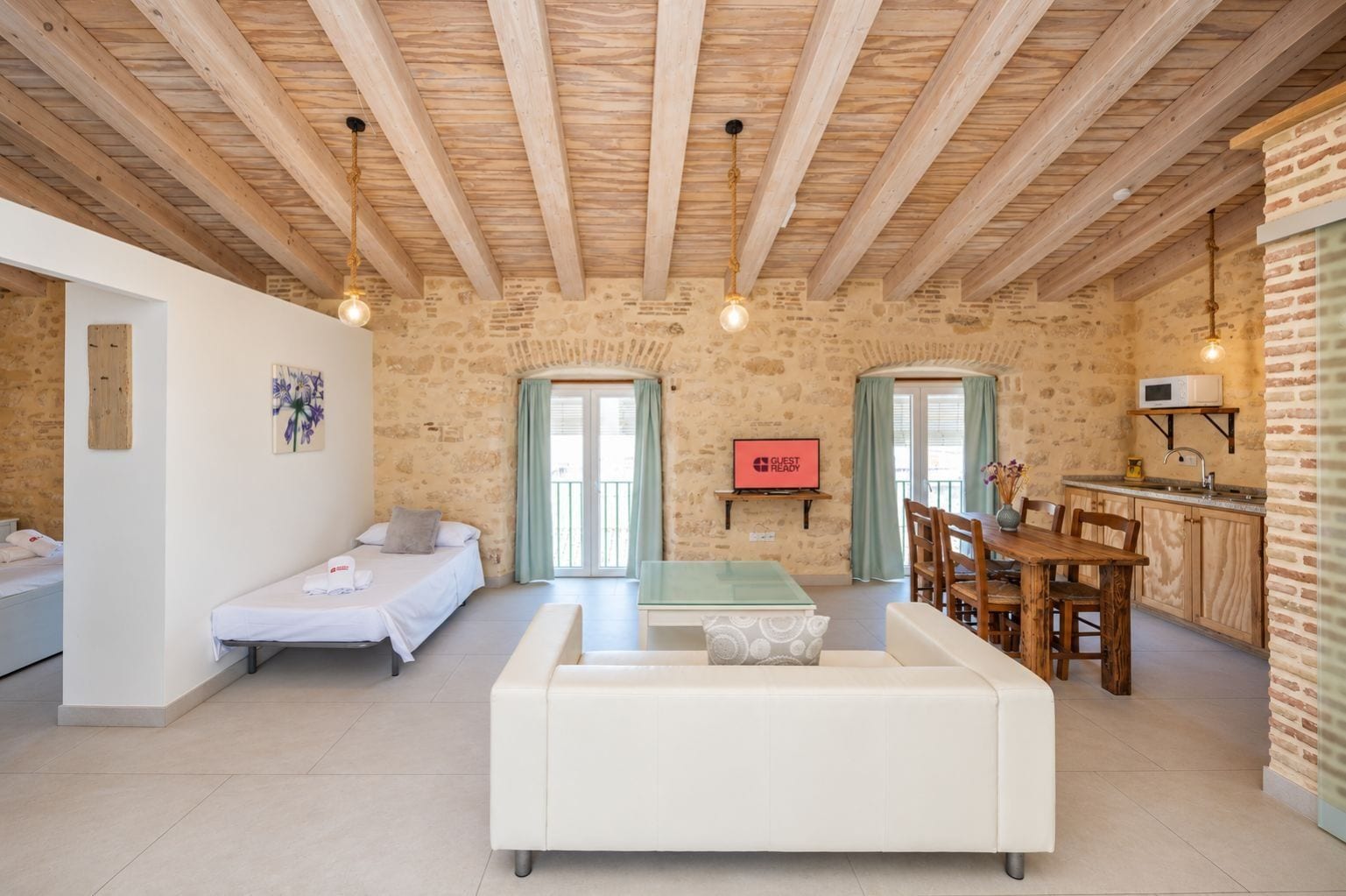 Una habitación acogedora con cama, sofá, mesa de comedor y zona de cocina.