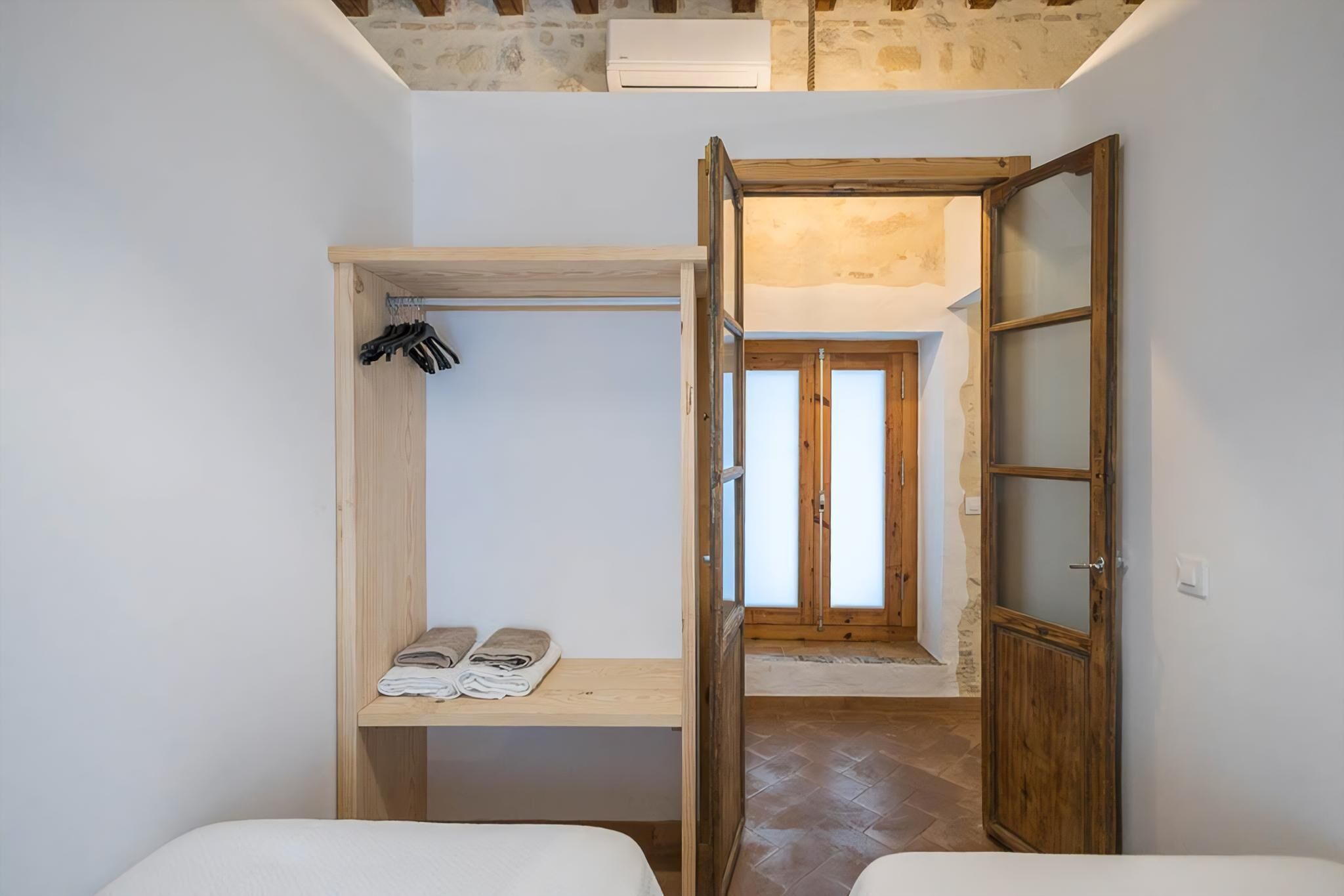 Una habitación pequeña con un banco de madera, una puerta con paneles de vidrio esmerilado y piso de baldosas.