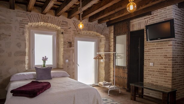 Una camera da letto con un letto, una lampada a sospensione, una TV e una porta in legno.