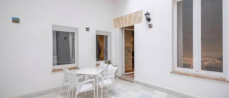 Un interior limpio y blanco con comedor, dos ventanas y una puerta que da al exterior.