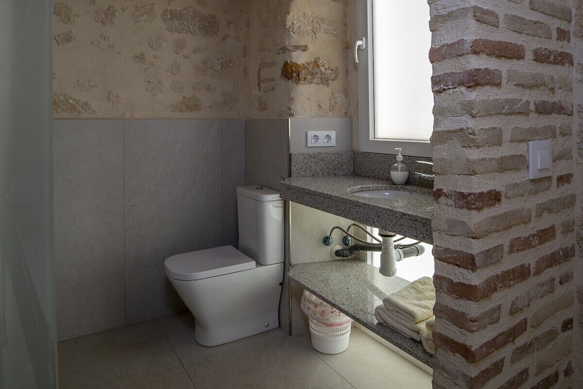 A compact bathroom with a toilet, a sink, and a window.