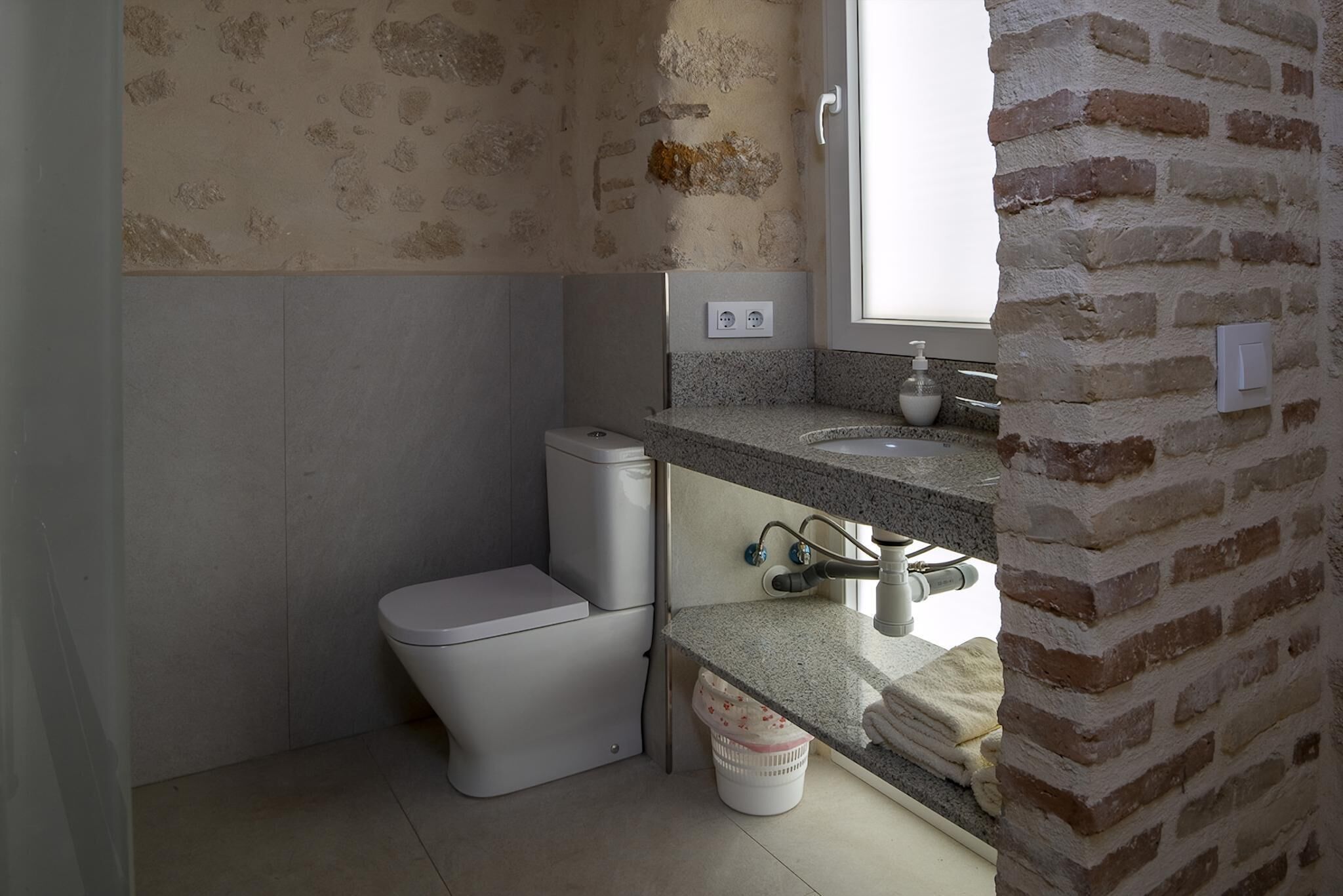 Un baño pequeño con inodoro, lavamanos y ventana.