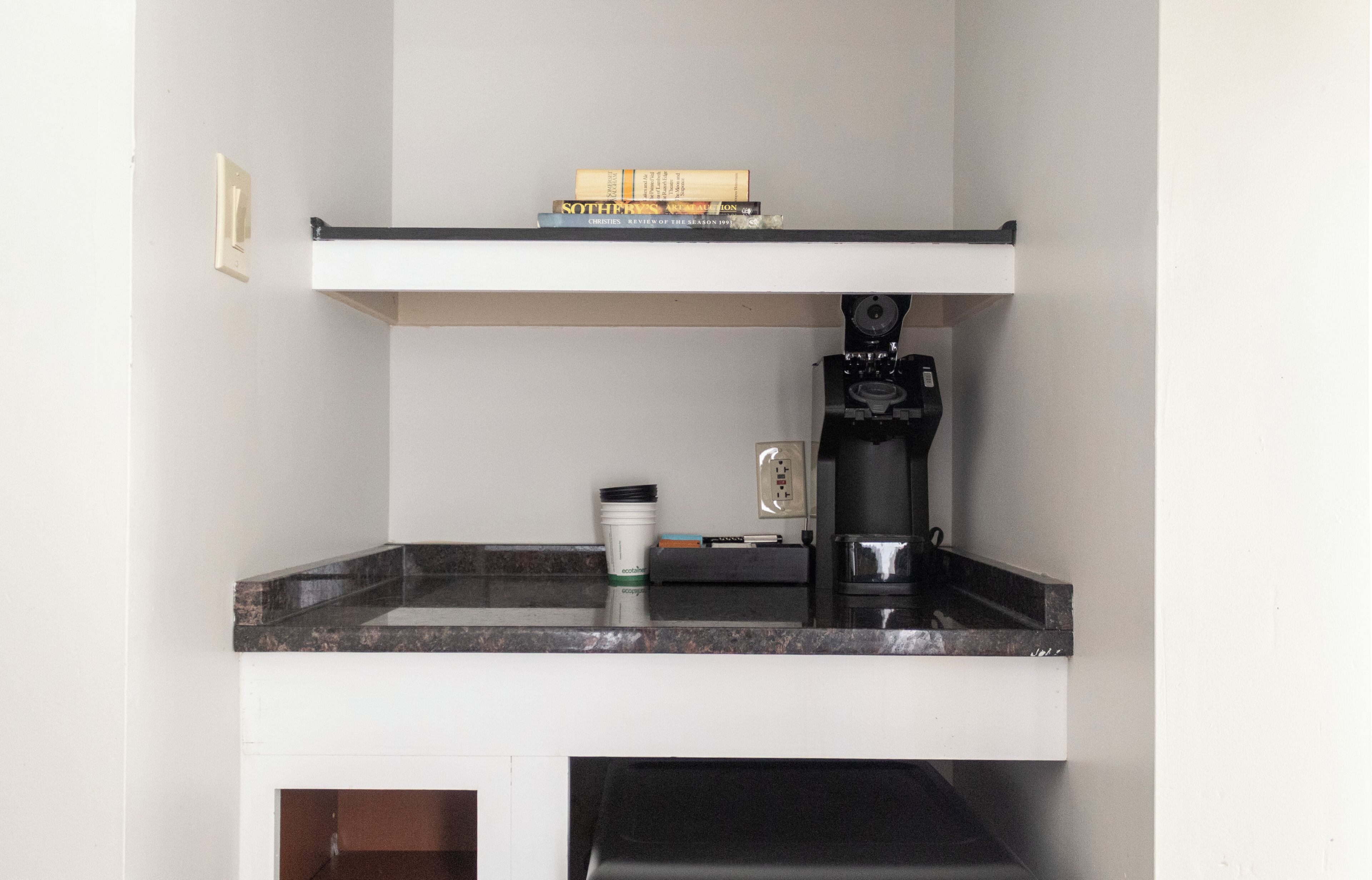 A kitchen with a coffee machine, a coffee cup, and a book on the counter.