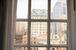 A view through a window with a grid pattern, displaying a cityscape with various buildings. - StayCozy at The Arco (Philadelphia)
