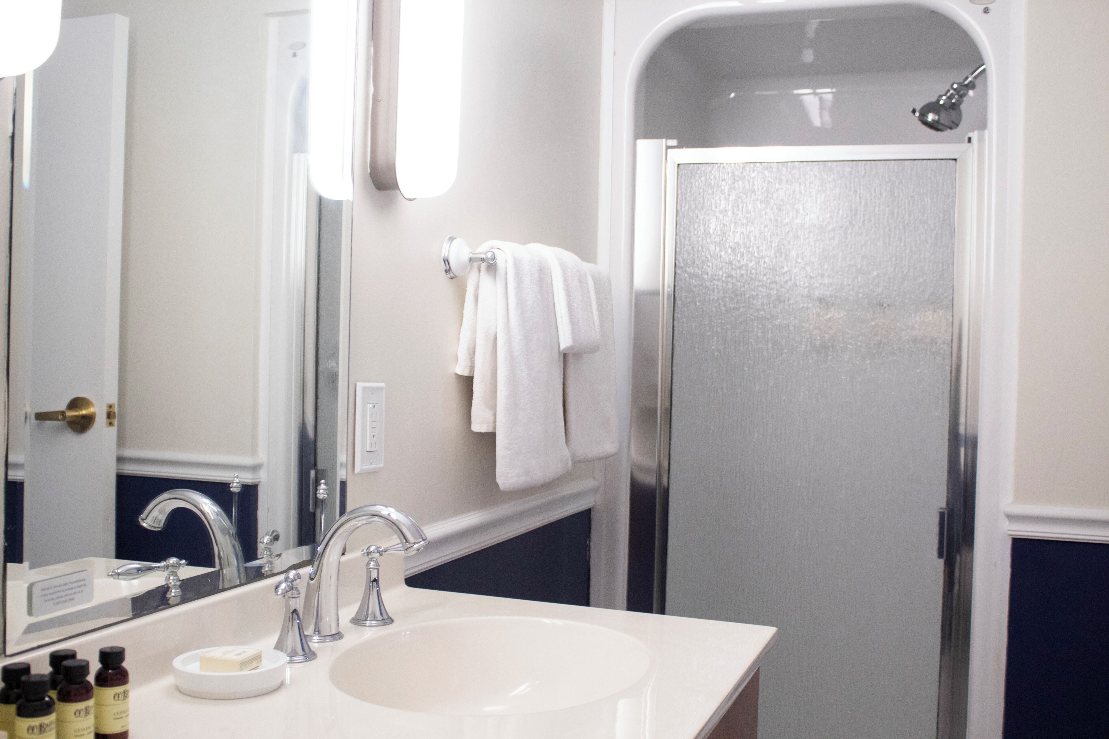 A bathroom with a white sink, a mirror, a towel rack, and a shower door.